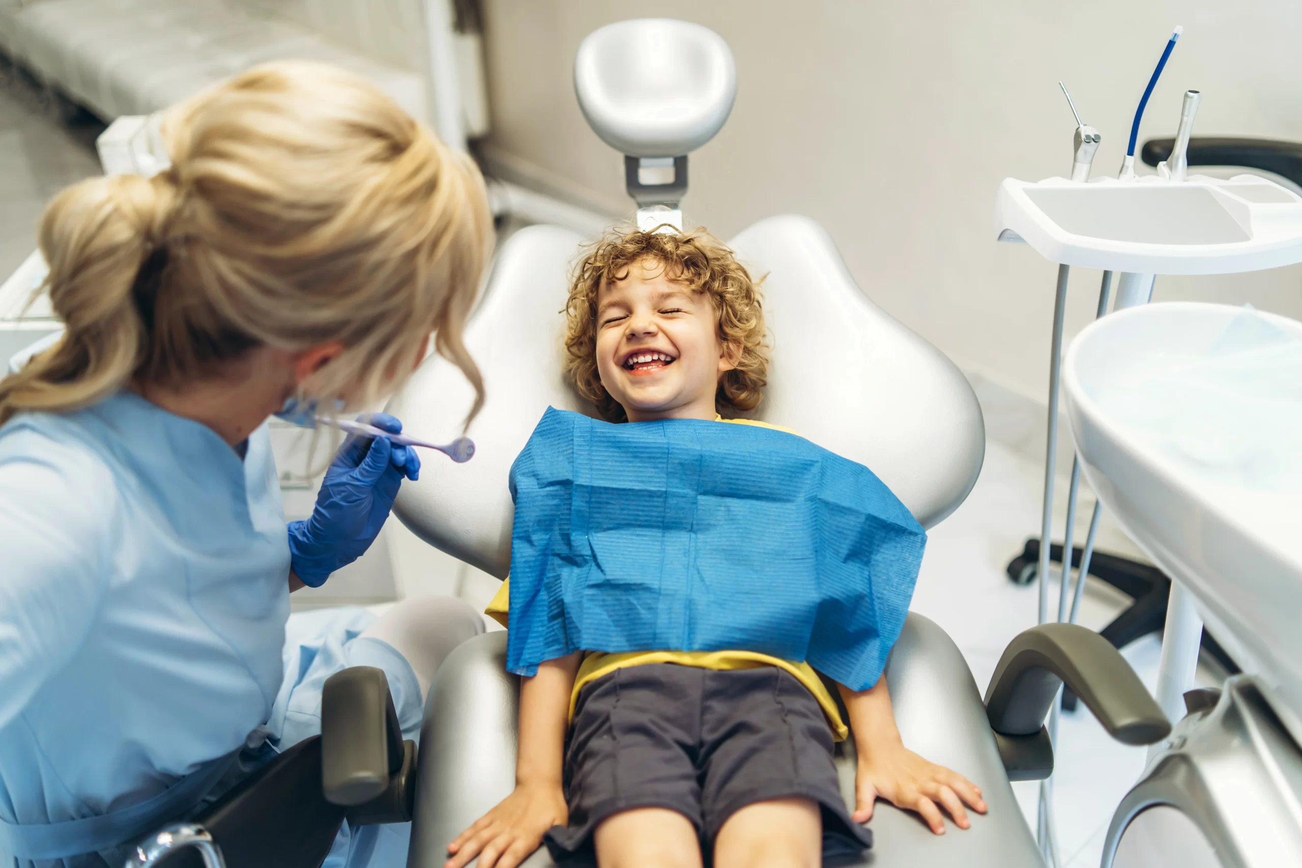 Child smiling in dental chair with dentist.