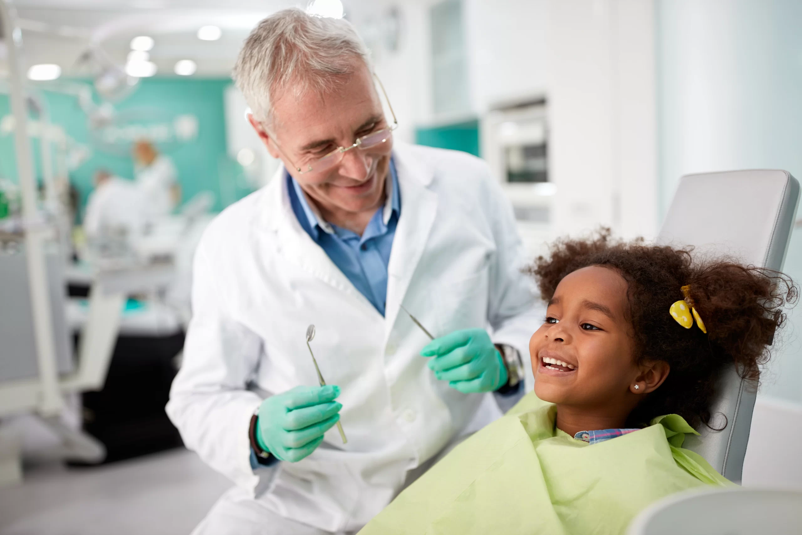 Dentist smiling at child in dental chair.