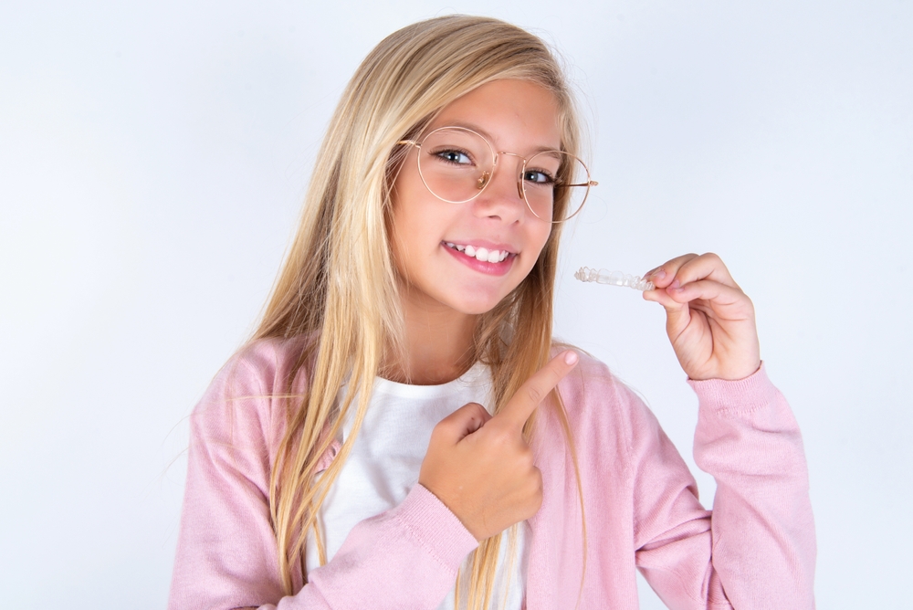 little,kid,girl,wearing,pink,jacket,over,white,background,holding