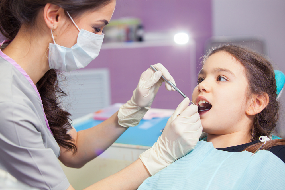 Dentist examining young girl's teeth.