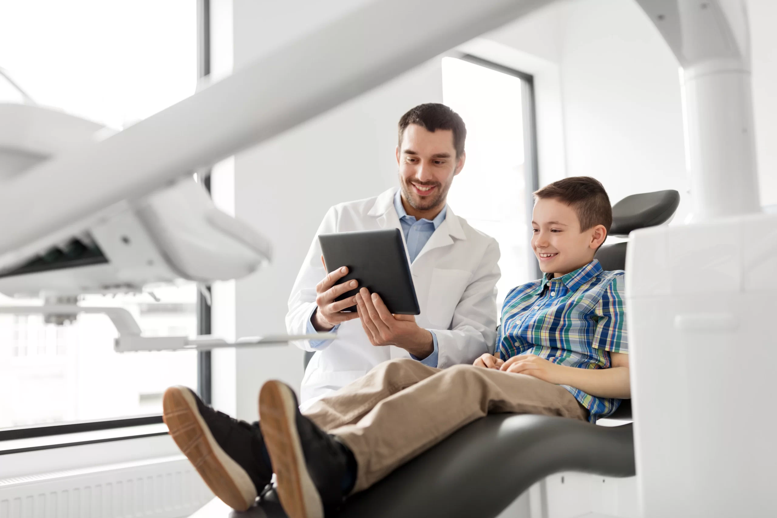 Dentist and child patient looking at tablet.