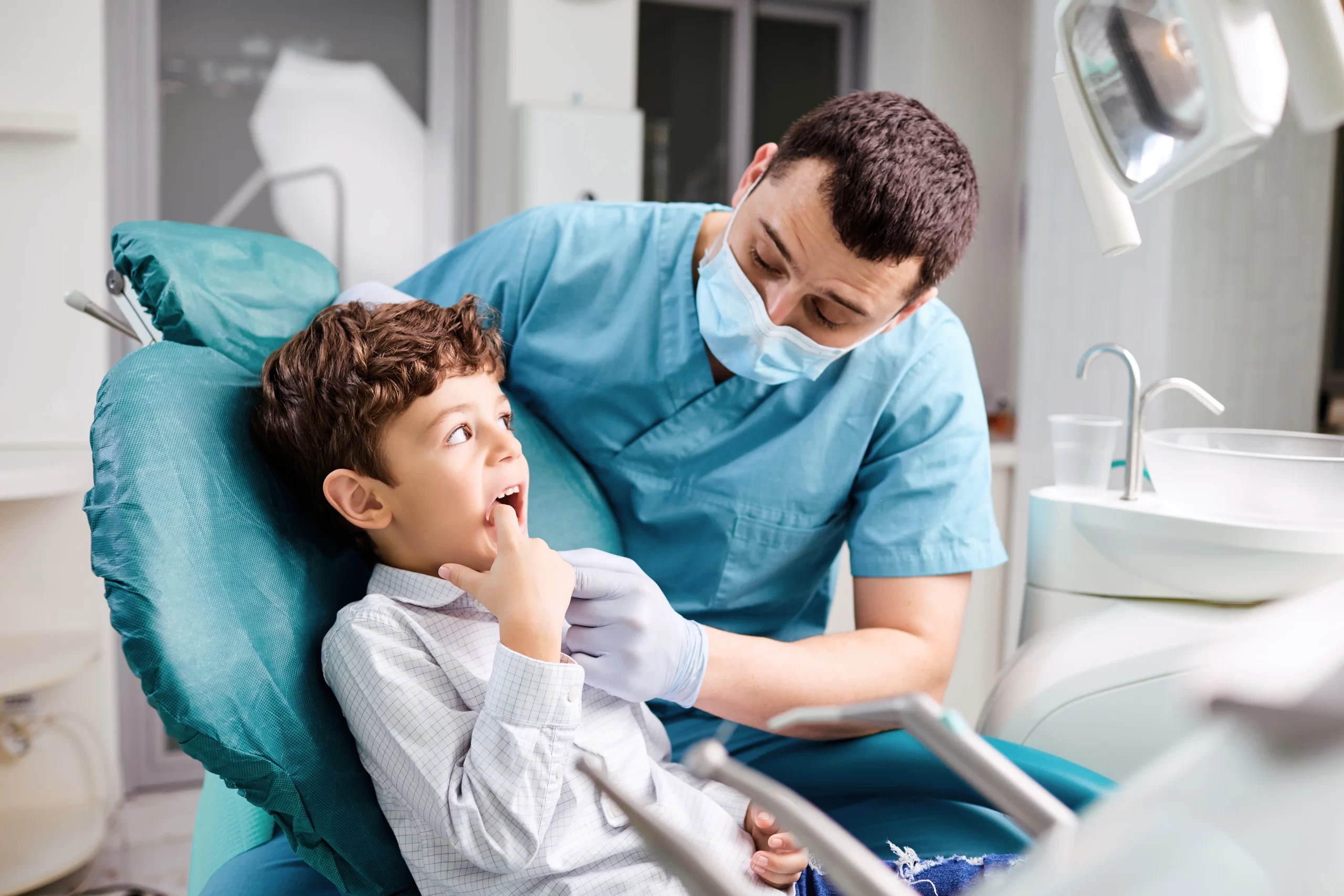 Dentist examining child's teeth in clinic. Teeth Extractions For Kids