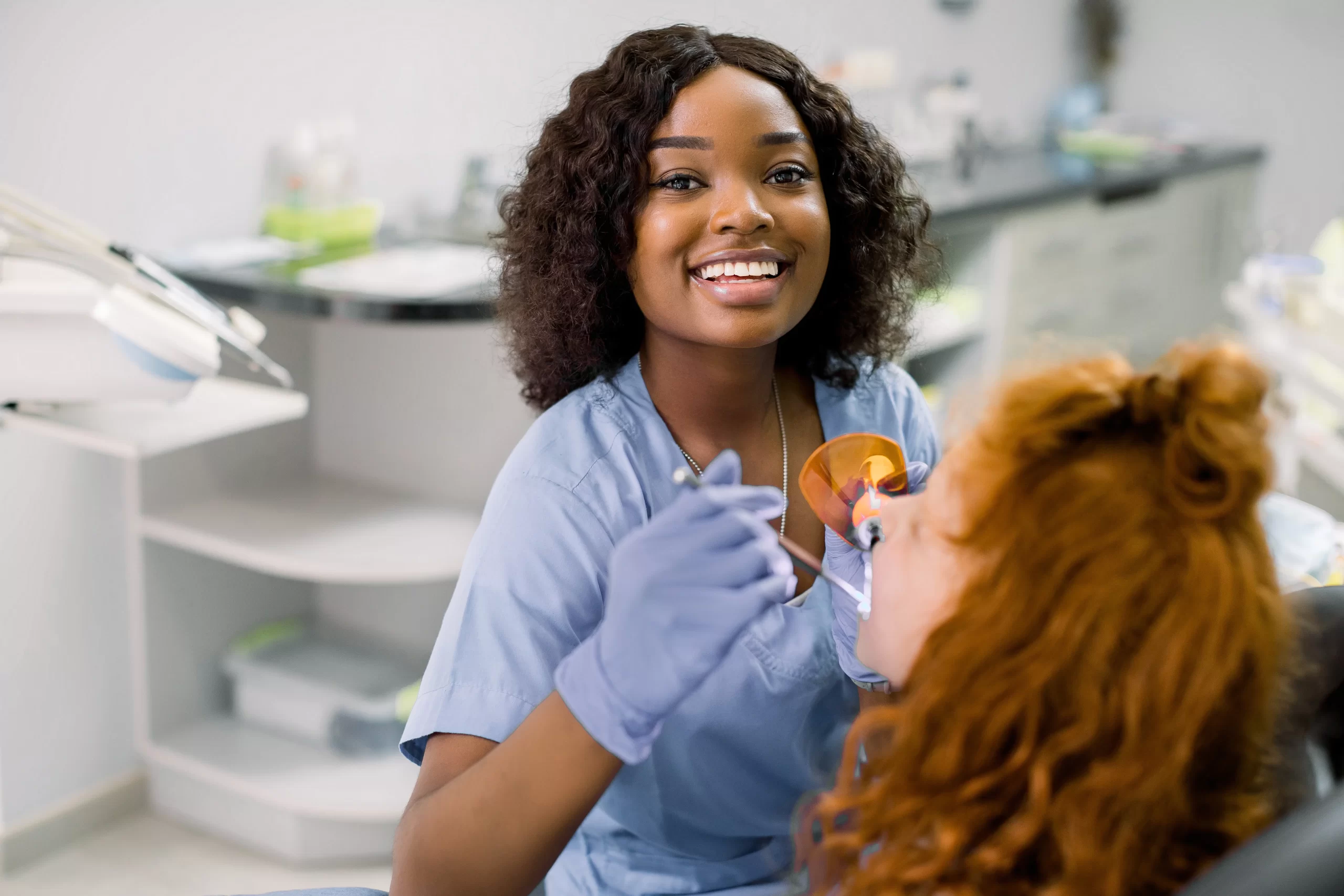 Smiling dentist treating a patient in clinic.