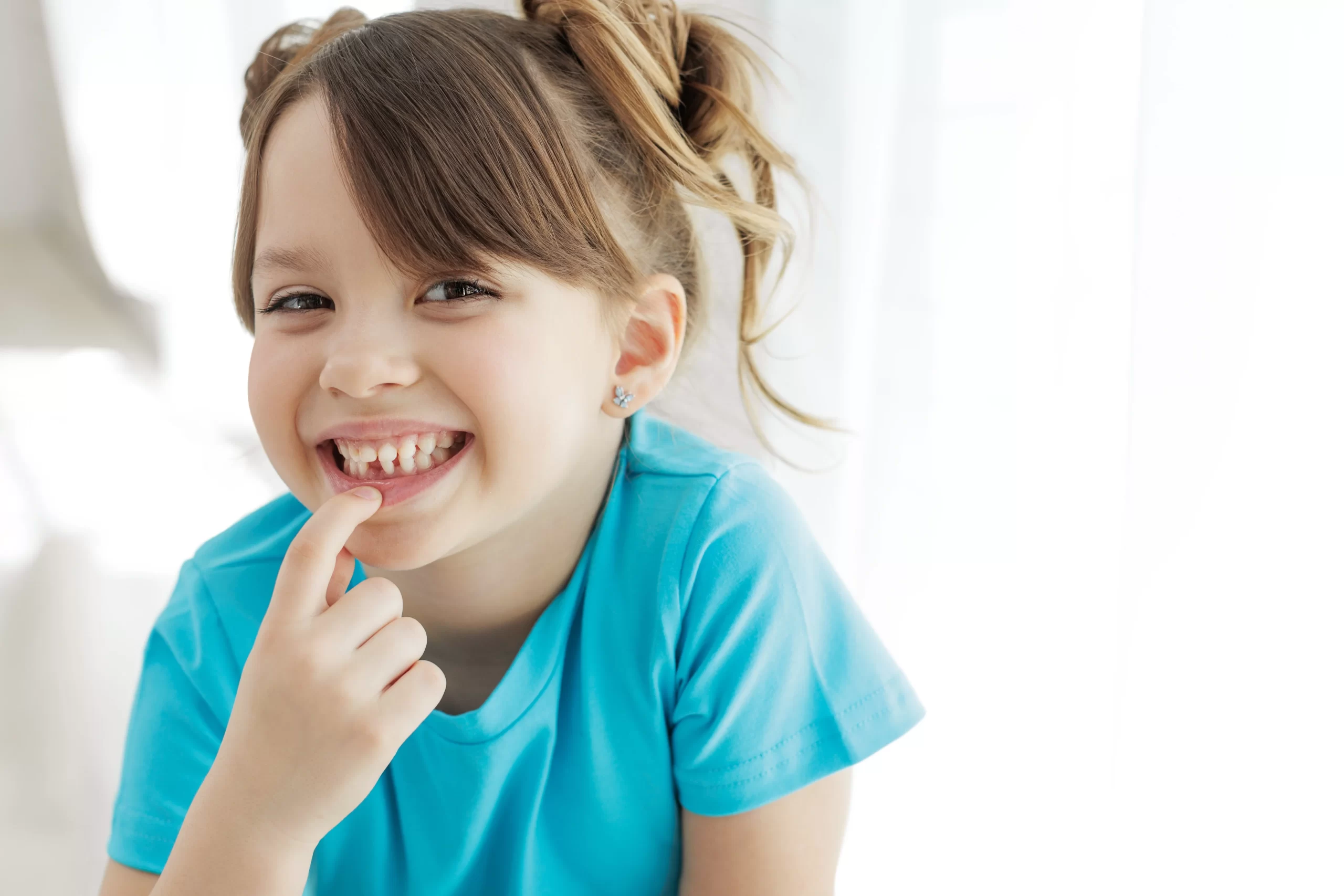 Smiling child in blue shirt with missing tooth.