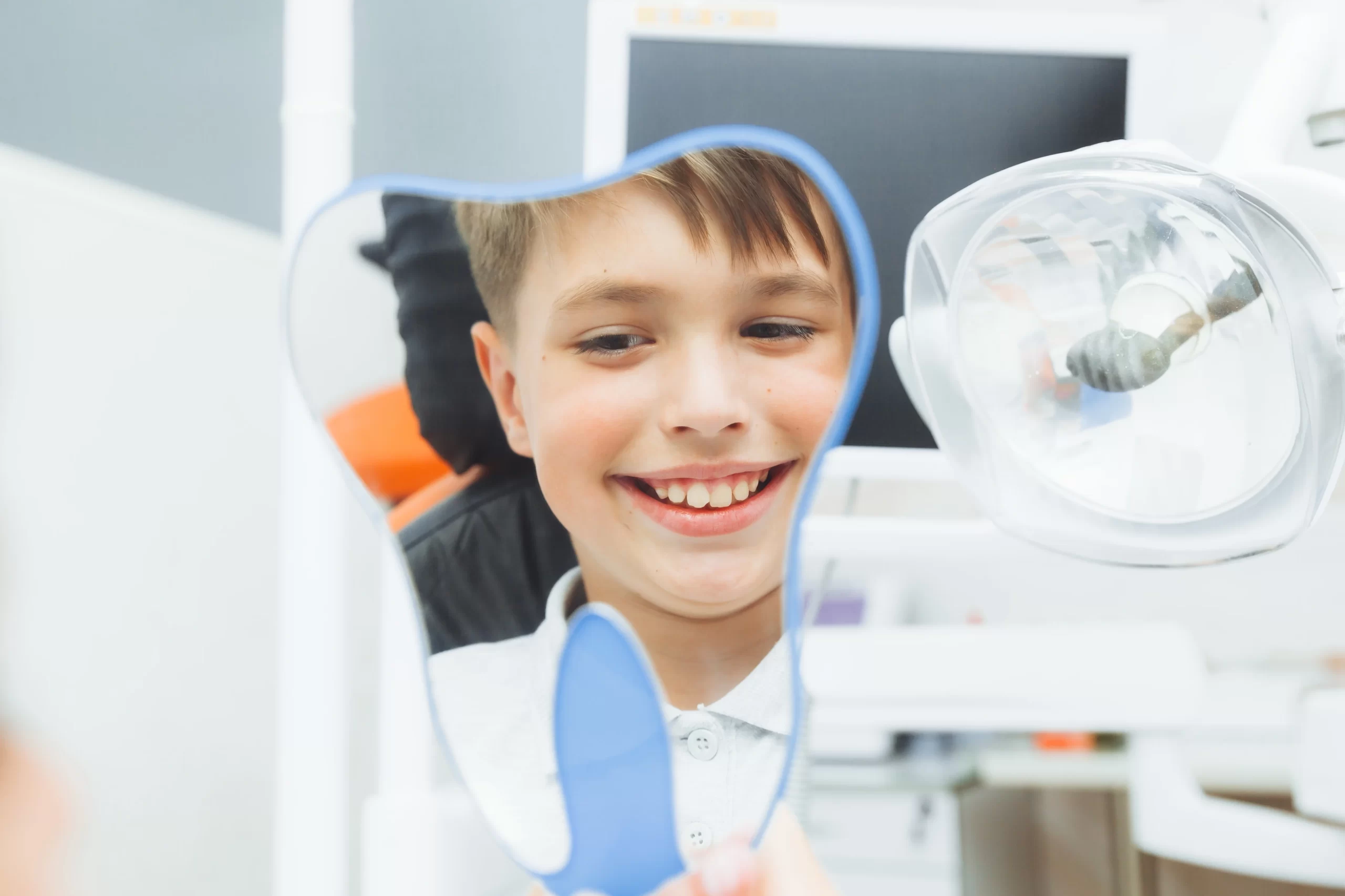 Smiling child looking in dental mirror