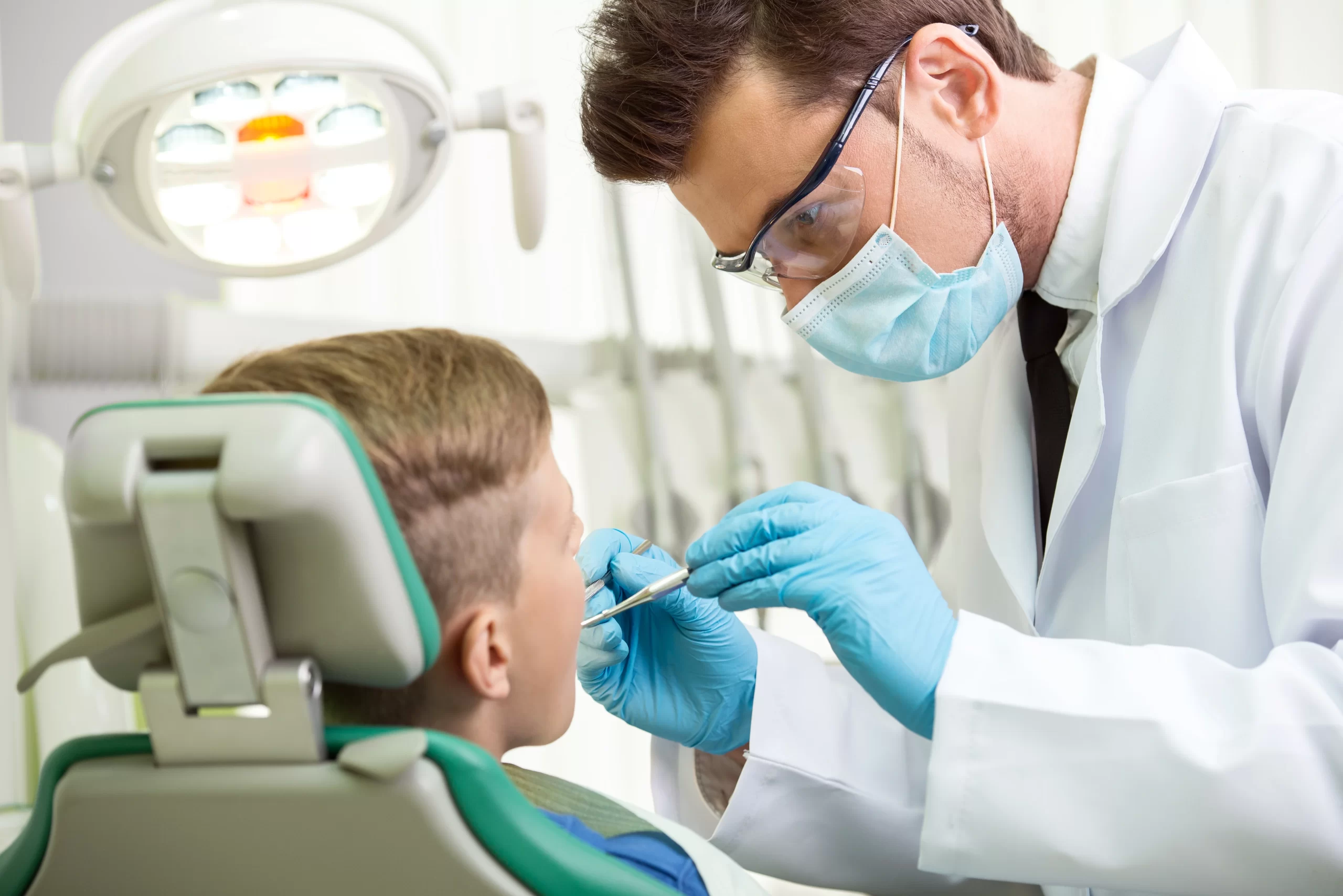 Dentist examining child's teeth in clinic using Nitrous Oxide For Kids