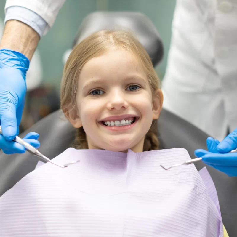 Smiling child at dentist with dental tools. Teeth Extractions For Kids