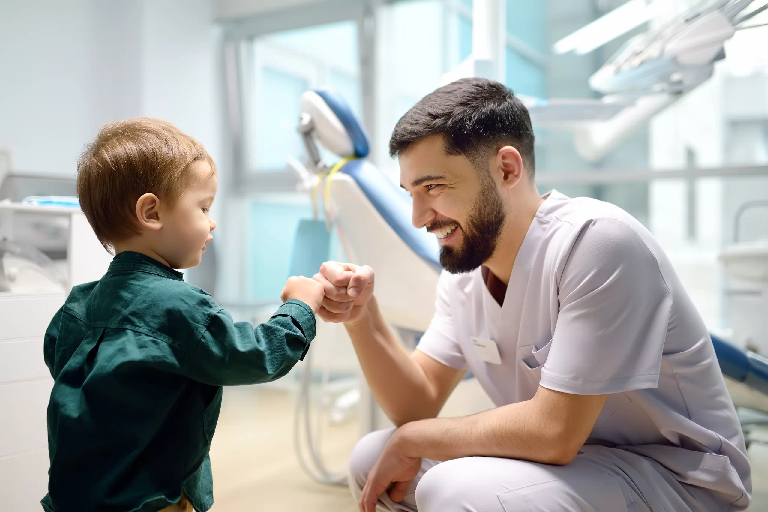 Dentist fist-bumping toddler in dental clinic.