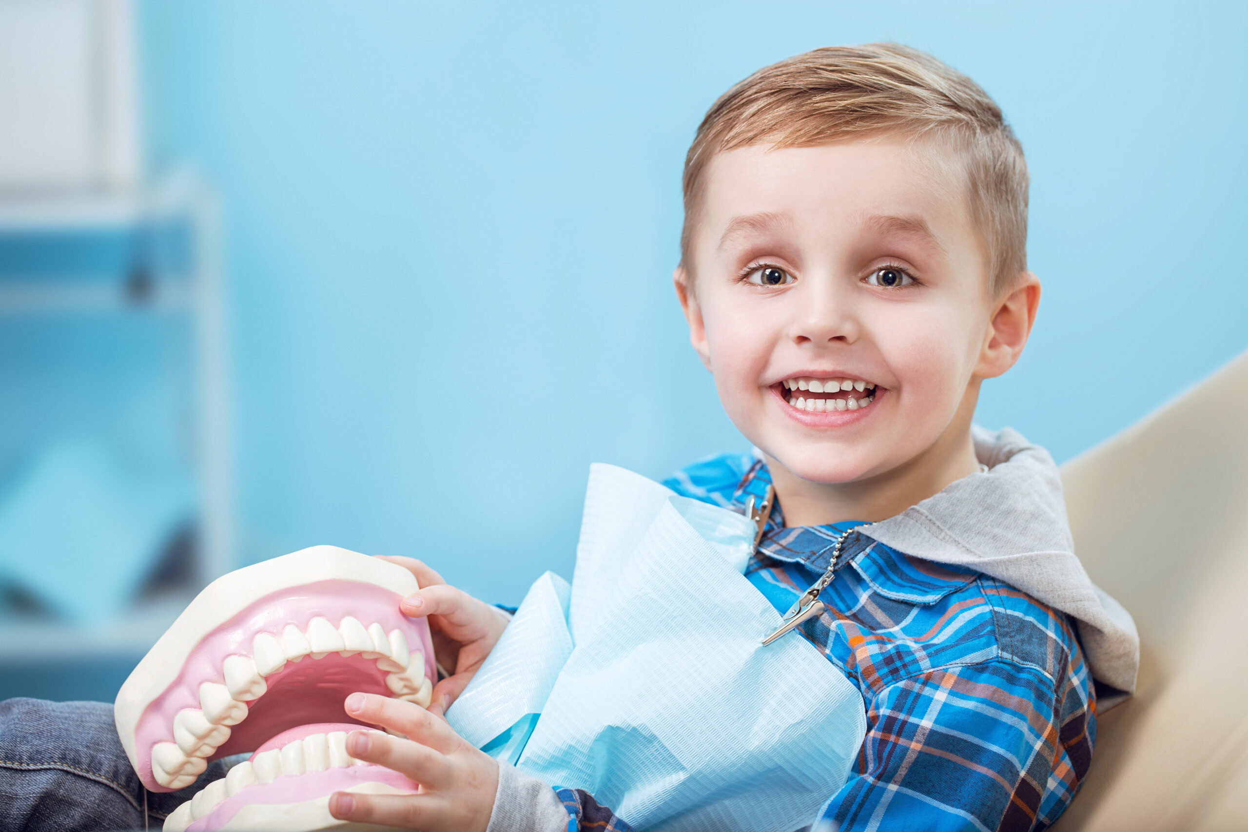 Smiling child with dental model at dentist office