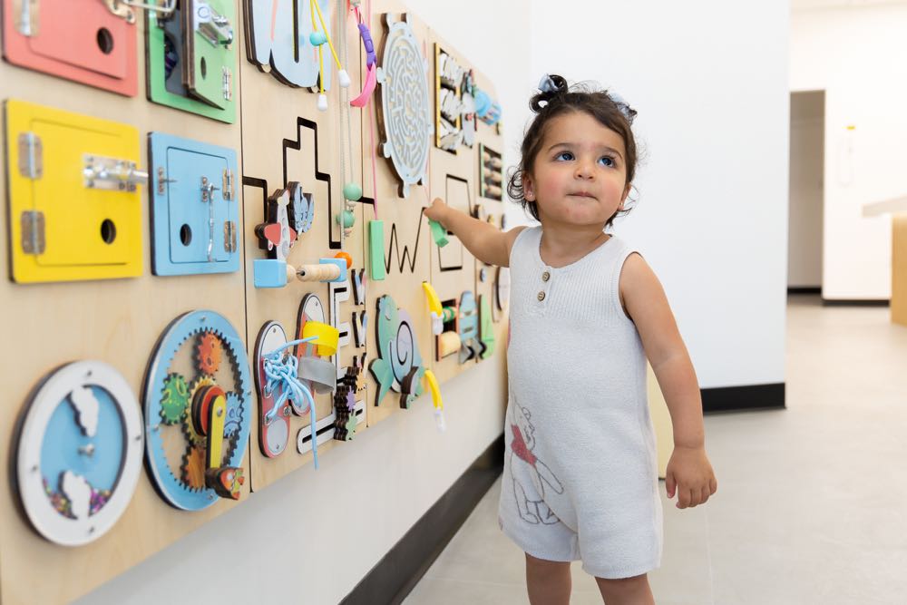 Child interacting with sensory activity wall.
