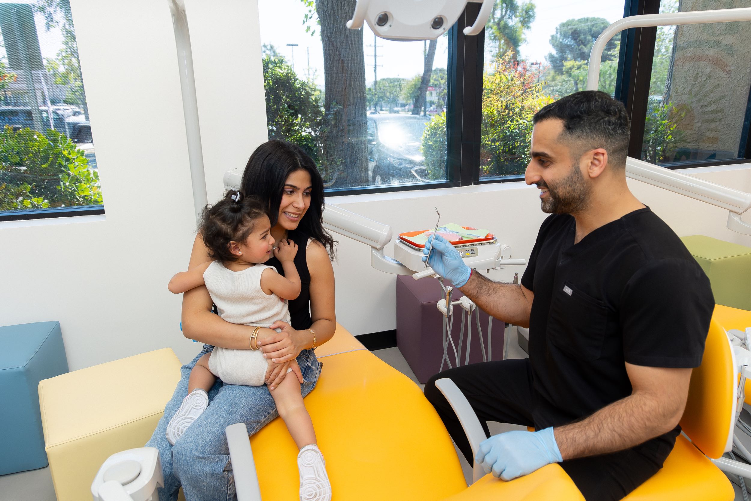 Dentist shows tool to child and mother.
