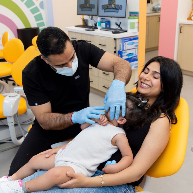 Dentist checks toddler's teeth with mother present.