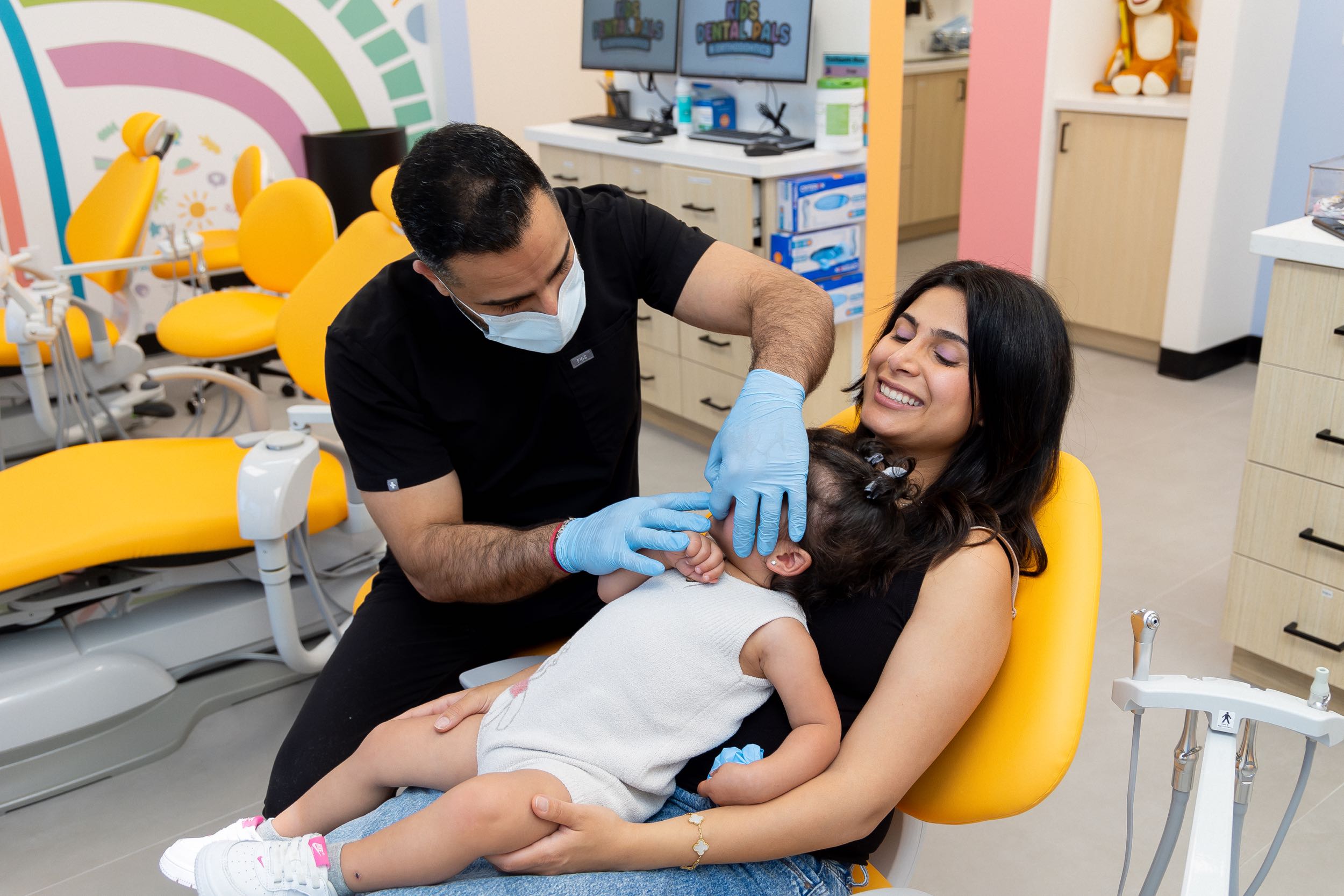 Dentist checks toddler's teeth with mother present.