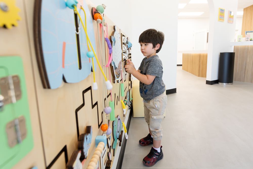 Child playing at educational activity wall