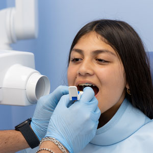 Dentist preparing young patient for dental X-ray.