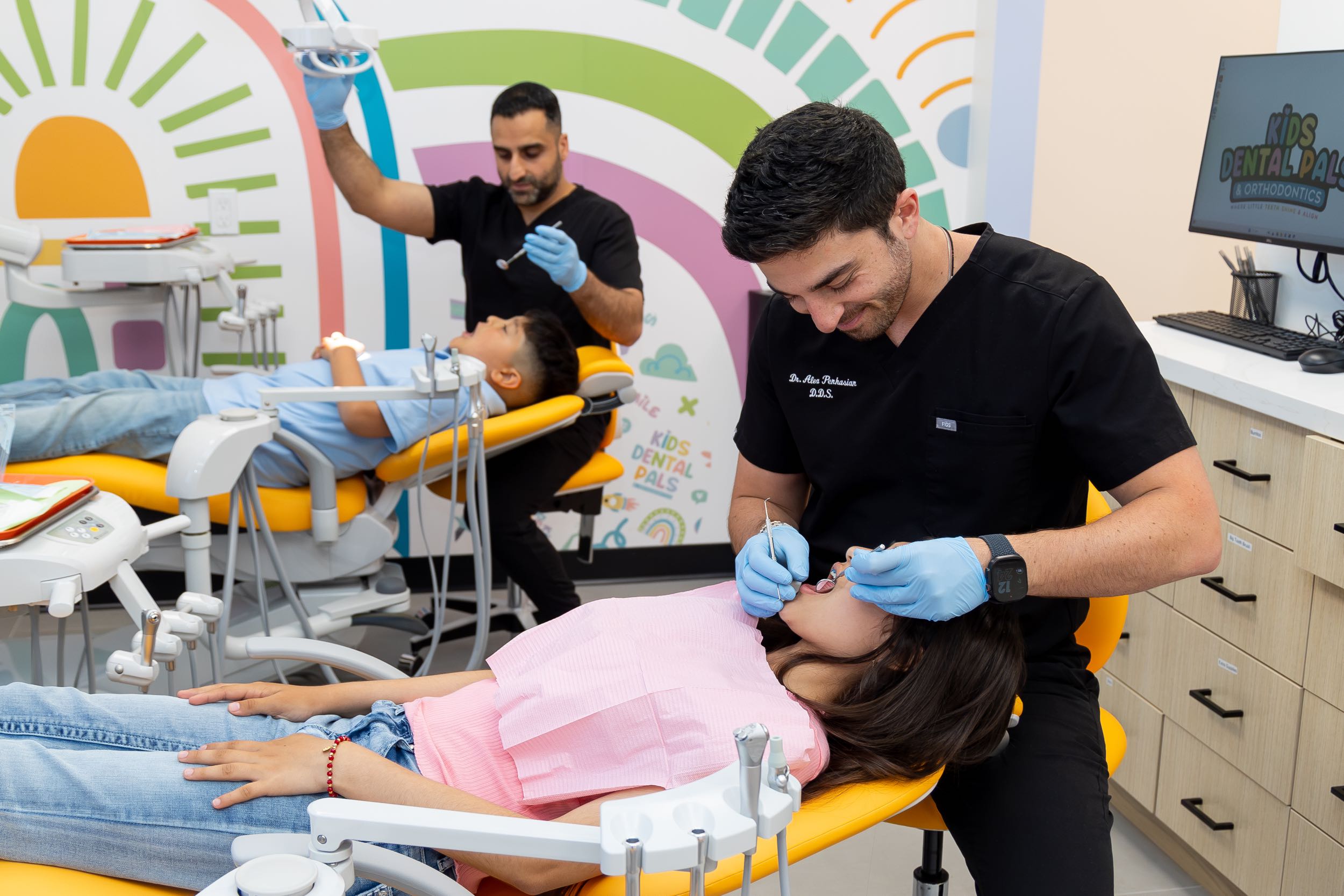 Dentists treating children in colorful dental clinic.