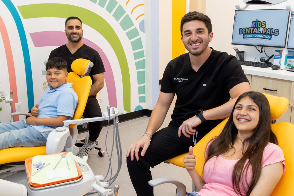 Children and dentists smiling in dental office.