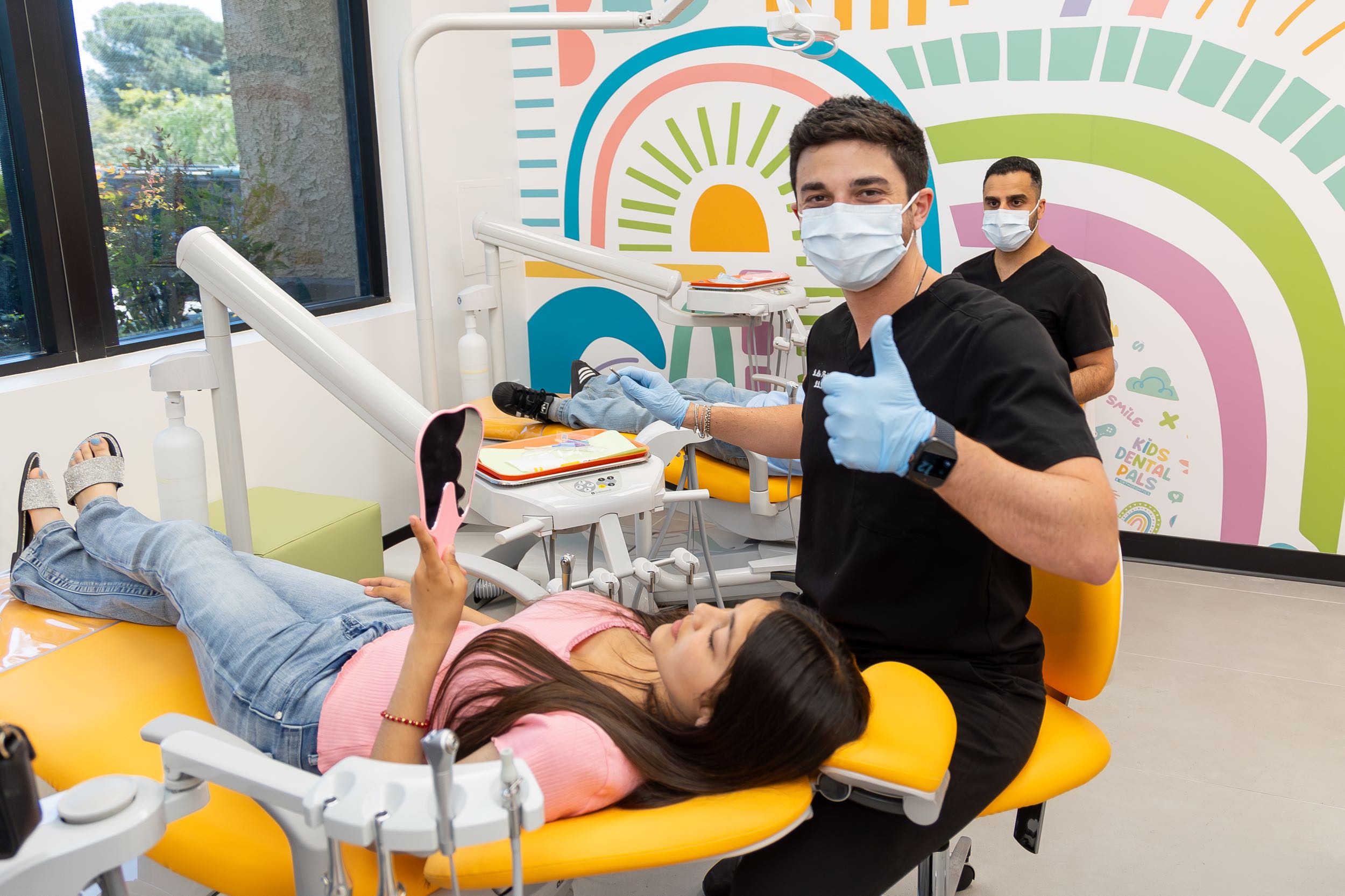 Dentists treating a patient in colorful clinic.