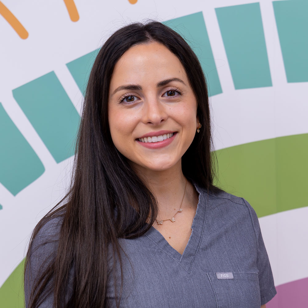 Smiling woman in a gray top with colorful background.